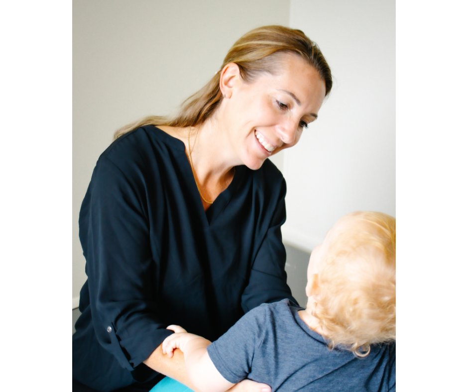 Ashley Lajoie, owner of Excel Therapy Services shown in a dark blue shirt sitting next to a child with blonde hair, both smiling in occupational therapy setting.