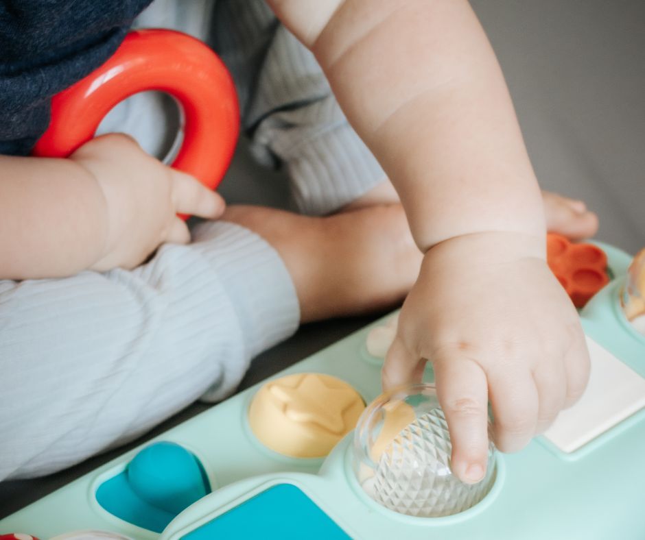 Child playing with a colorful toy set, focusing on hands interacting with the toys.