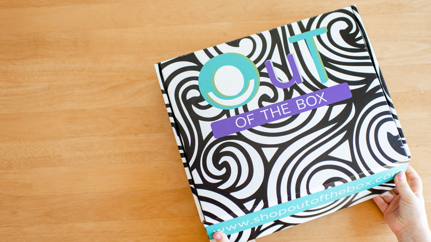 OuT of the Box occupational therapy box for children with a black and white pattern and colorful text on a wooden surface