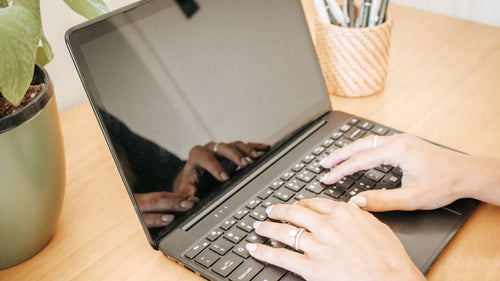 Person typing on a laptop at Excel Therapy Services office, with a plant and pen holder in the background
